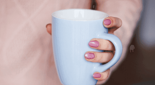 A hand holding a light blue coffee cup